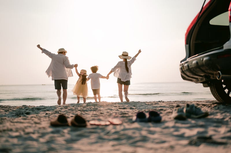 Family vacation holiday, Happy family running on the beach in the sunset. Back view of a happy family on a tropical beach and a car on the side. - stock photo