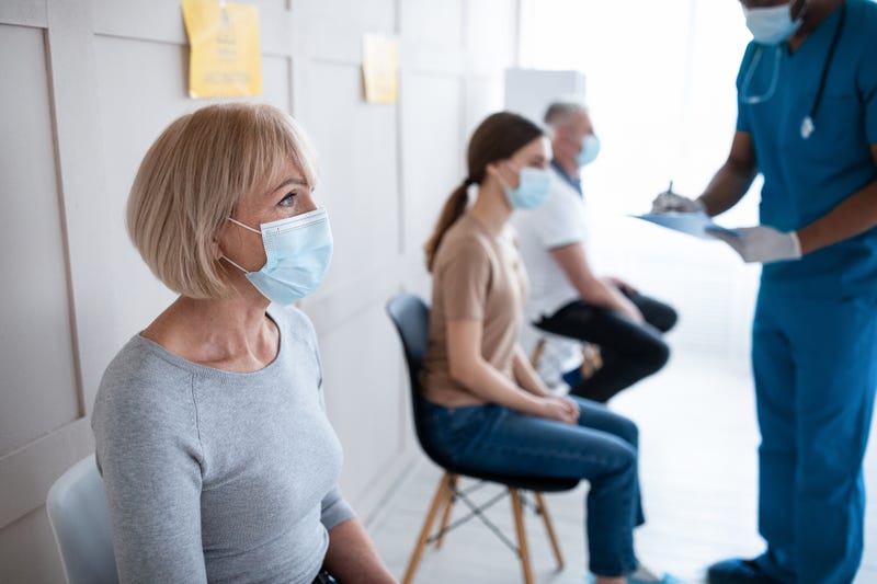 Woman waiting for COVID-19 vaccine shot stock photo. 