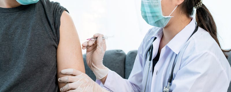 Asian professional doctor injecting a Coronavirus 2019-nCoV or COVID-19 vaccine at male patient arm close up, COVID19 vaccinating about protecting and build antibody - immunity against Coronavirus.