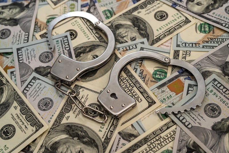 handcuffs on pile of hundred dollar bills