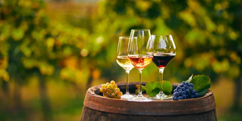 glasses of wine on wooden barrel with vineyard in background