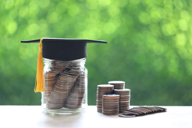 Graduation hat on the glass bottle with Stack of coins money on nature green background.