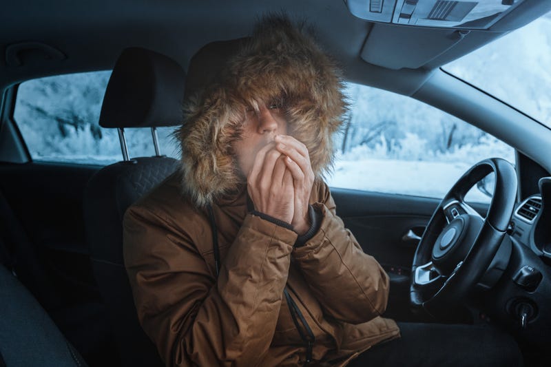 Man in jacket tries to keep warm in his car during the winter