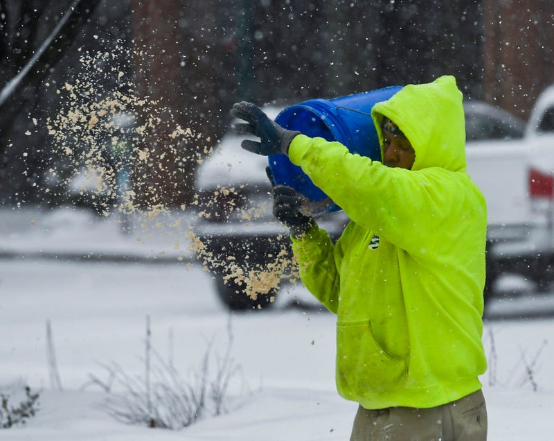 An employee from the Reading Public Works department spreads salt from a bucket on sidewalks during a snowstorm in Reading, Pennsylvania, Feb. 18, 2021.