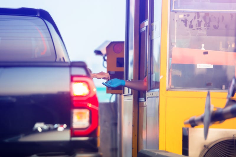 Woman pays money to a cashier for a toll road toll gate motorway entrance.