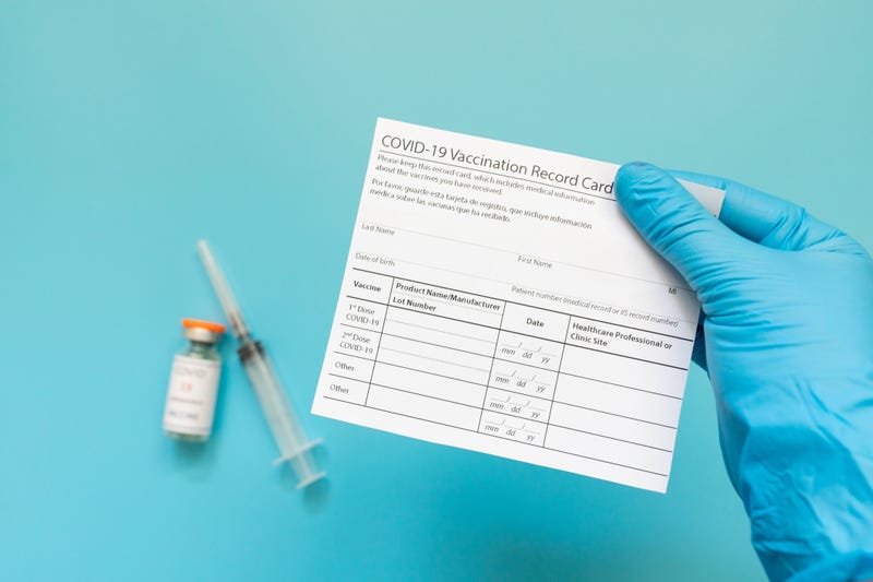 Doctor is holding a vaccination record card and coronavirus vaccine vials
