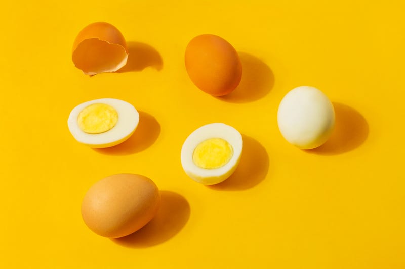 Hard boiled eggs and brown shells on a clean yellow background. 