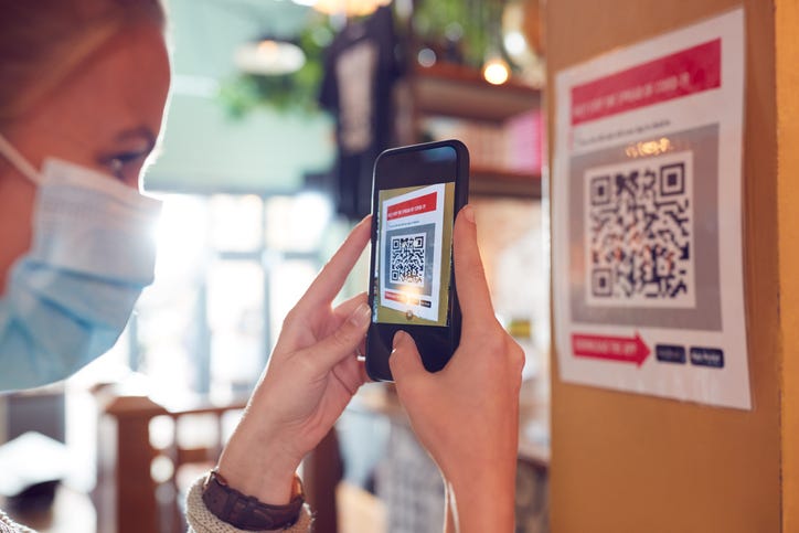 Woman In Mask Checks QR Code.