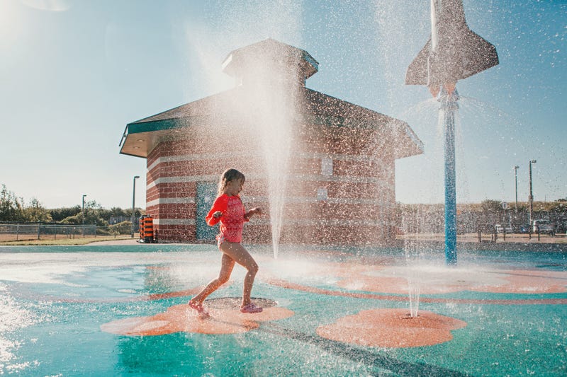 Girl running through splash pad at a park.