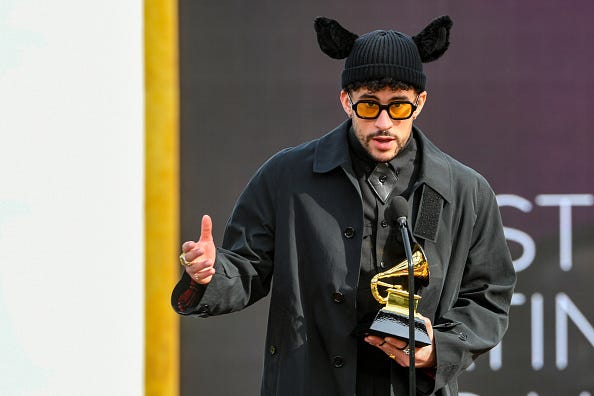 singer bad bunny in front of a mic holding a Grammy award