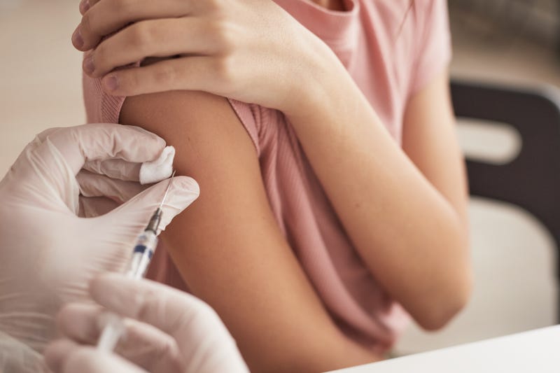 A young girl is vaccinated by a doctor.