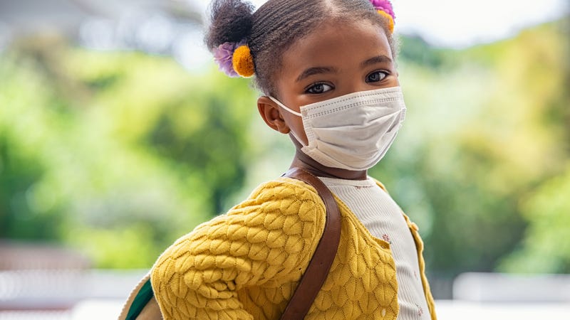 A girl about to attend school, wearing a face mask