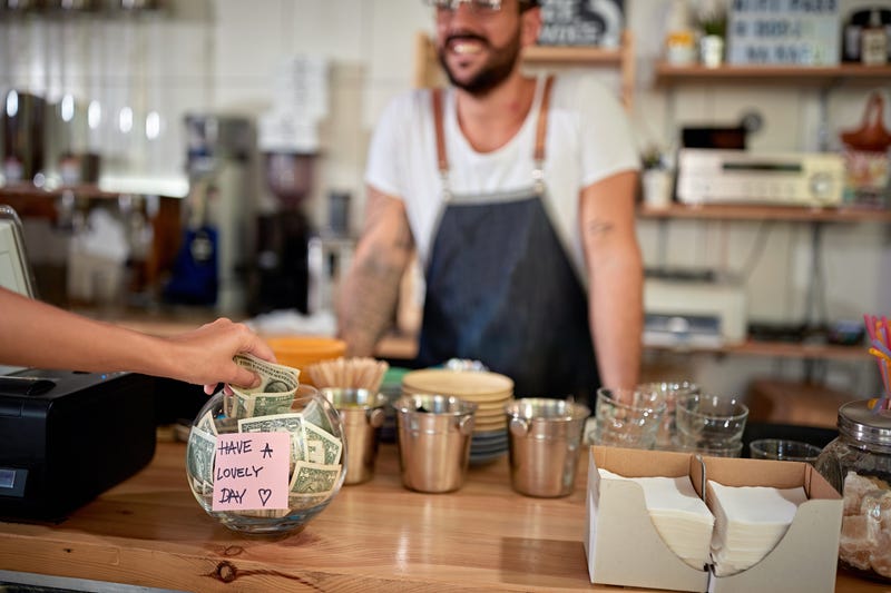 person putting money in a cafe tip jar