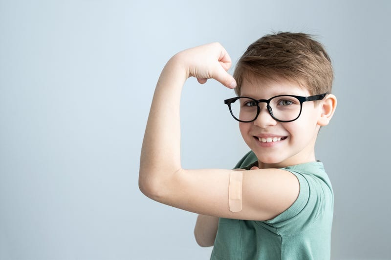A boy shows off his bandaid after getting the COVID-19 Vaccine
