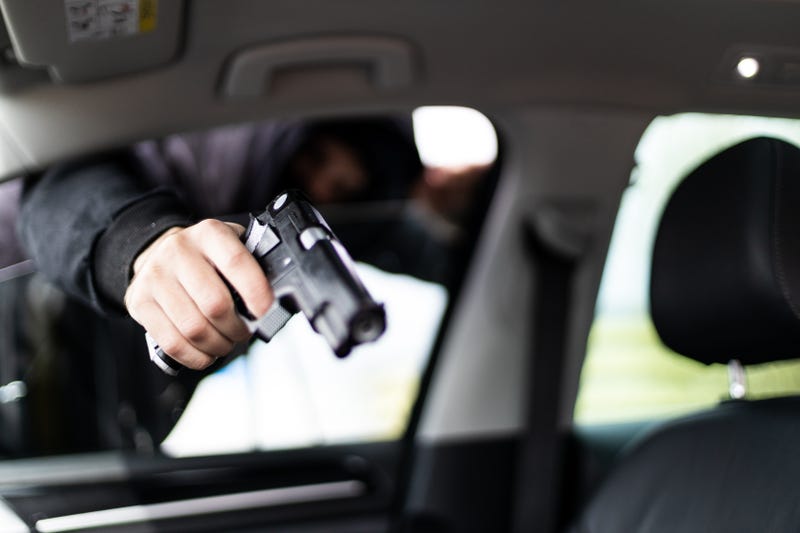 A man robbing a car with a gun.