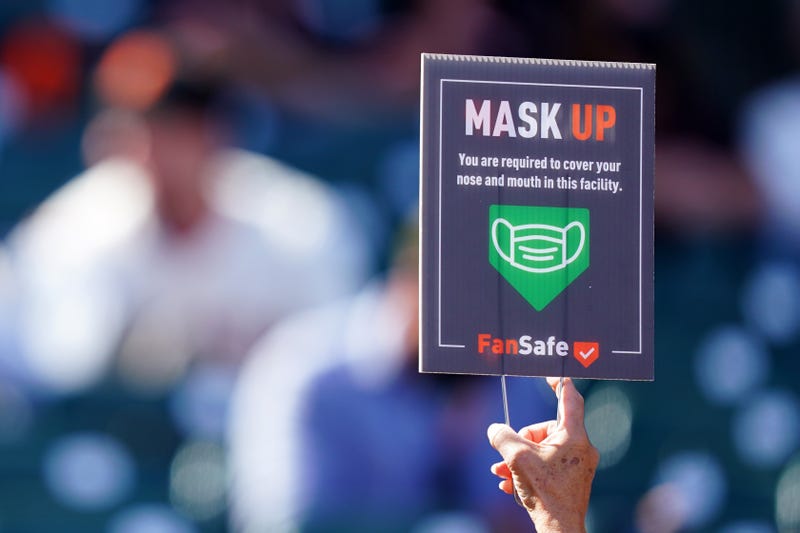An usher holds up a sign reminding fans to wear masks during the game between the San Francisco Giants and the Colorado Rockies at Oracle Park on April 11, 2021 in San Francisco, California.