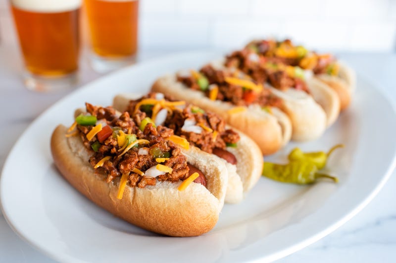 plate of chili dogs with glasses of beer in background