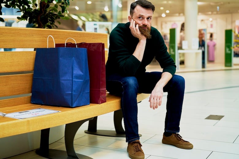Bored man sitting on bench in shopping mall