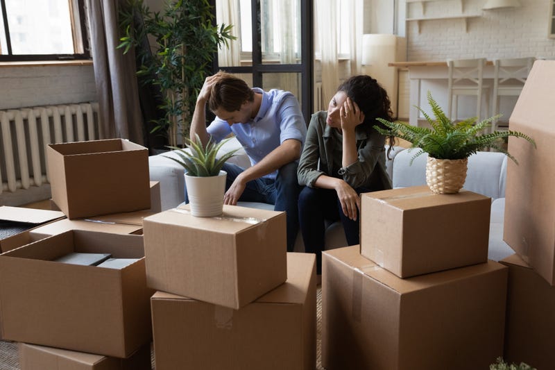 Unhappy frustrated couple sitting on couch with cardboard boxes, eviction, family having problem with dwelling, money or mortgage, worried woman and man lost home, bankruptcy or debt concept