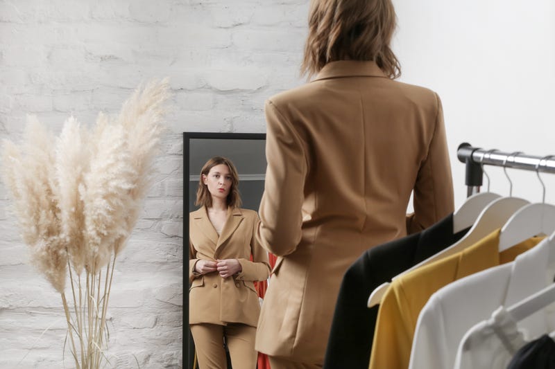 woman trying on a blazer in a mirror
