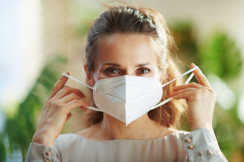 female in grey blouse wearing KN95 mask