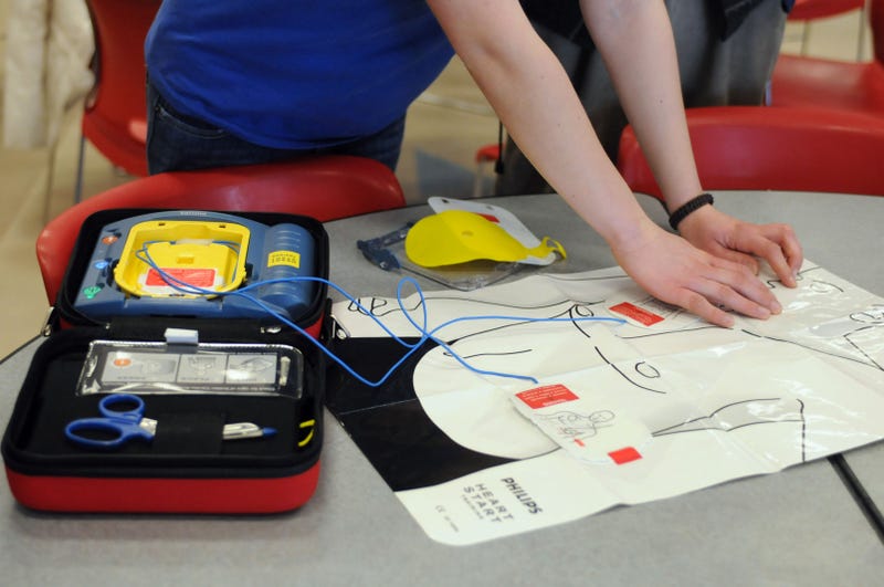 A person practices putting the patches of an AED onto a plastic cutout.