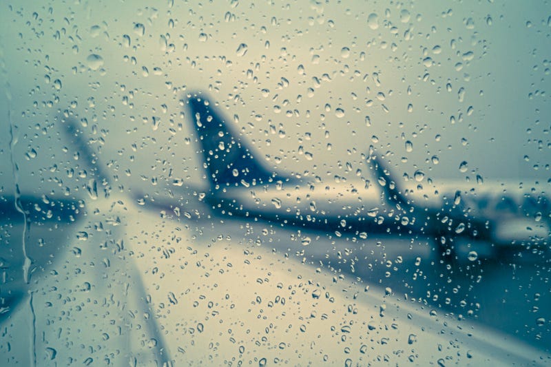 Raindrops on the glass against the background of a wing and a standing plane