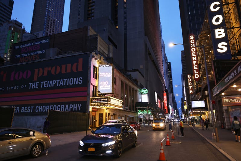 Cars drive past theater houses in the Theater District in Manhattan