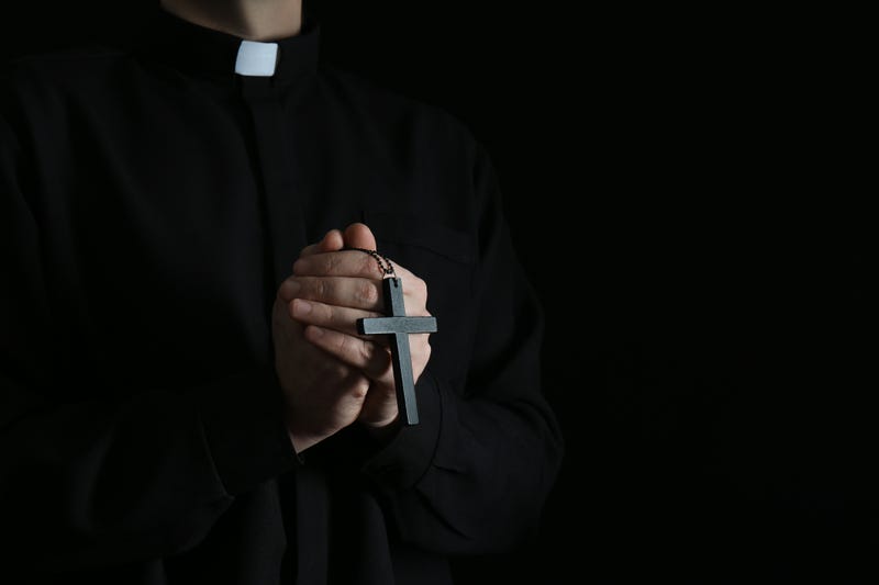 Priest with cross on dark background, closeup. Stock image. 