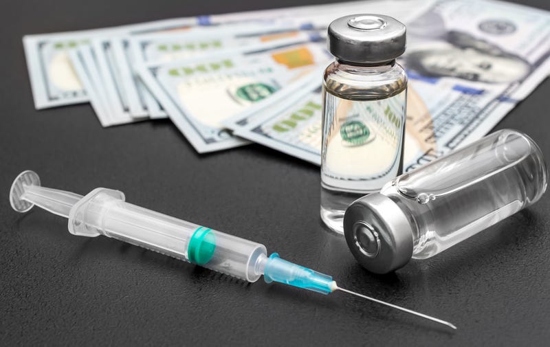 Vaccine vials with syringe and dollar bills on black. Close up.