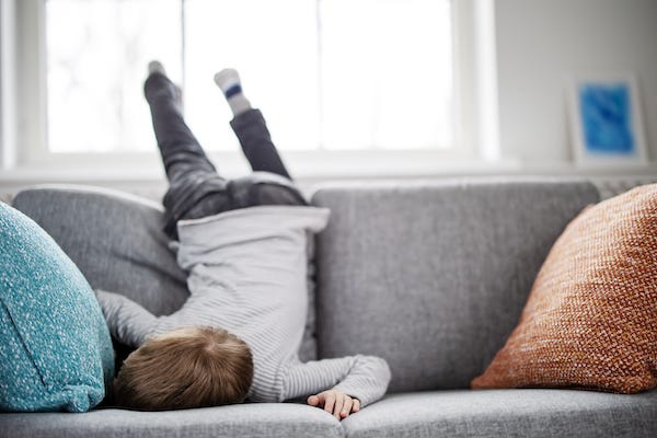 Bored kid with his face laying in the couch