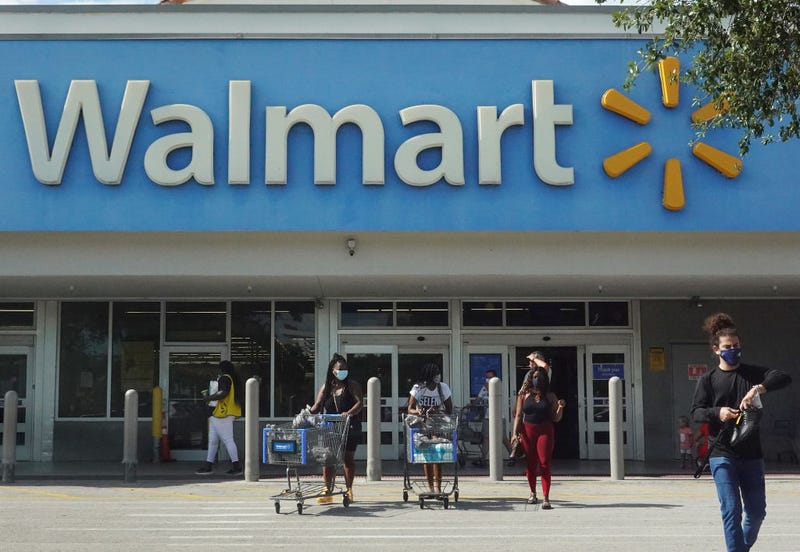 People wearing protective masks walk from a Walmart store.