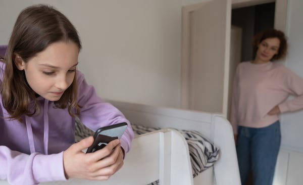 Young girl on phone ignoring her mom