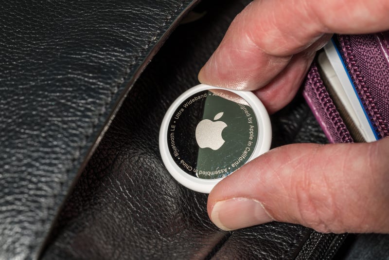 An Apple Airtag being placed in a purse.