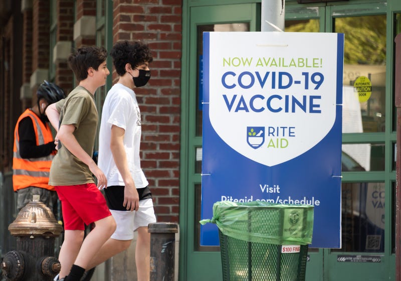 People walk by a sign that reads, "Now available! COVID-19 vaccine" in TriBeCa on May 27, 2021 in New York City. On May 19, all pandemic restrictions, including mask mandates, social distancing guidelines, venue capacities and restaurant curfews were lifted by New York Governor Andrew Cuomo.