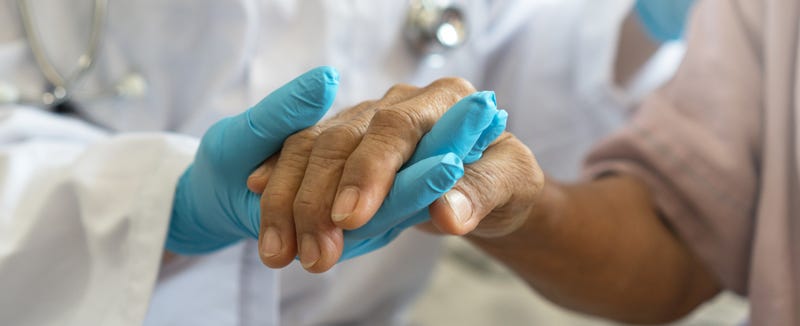 FILE: A doctor holds a patient's hand.