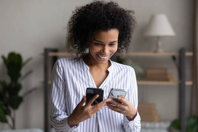 Woman holding two smartphones.