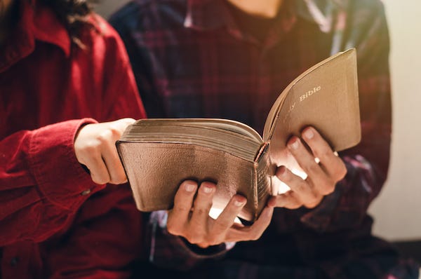 Young man and woman reading the bible together