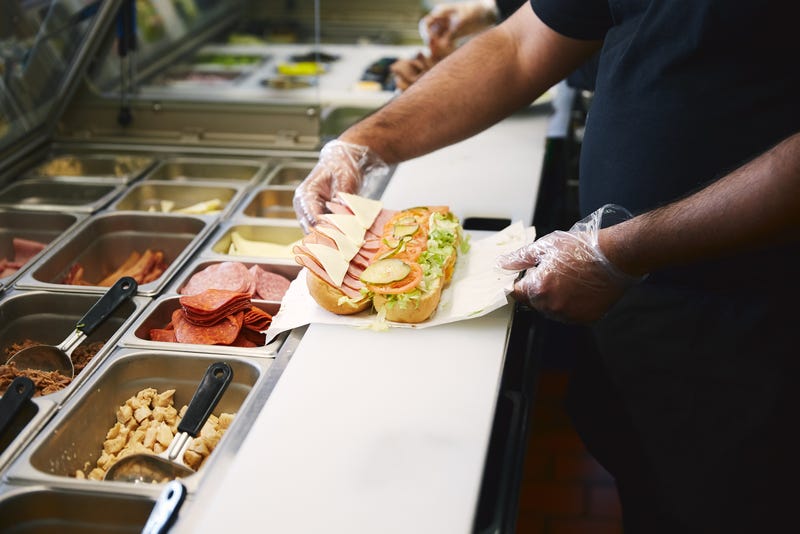 man preparing sandwich at restaurant counter