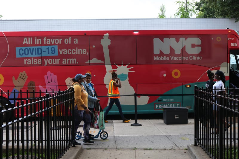 People walk past a mobile vaccination site on Flatbush Avenue on June 09, 2021 in the Flatbush neighborhood of the Brooklyn borough on New York City