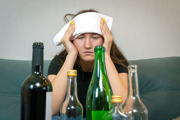 Young woman with a hangover holding a towel on her head