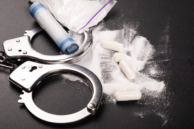Drugs and handcuffs shown on a dark background
