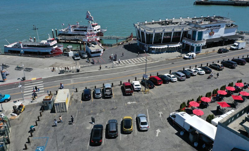 In an aerial view, cars and tables fill a parking lot next to a restaurant and bay cruise terminal at San Francisco's Fisherman's Wharf tourist destination on June 14, 2021 in San Francisco, California.