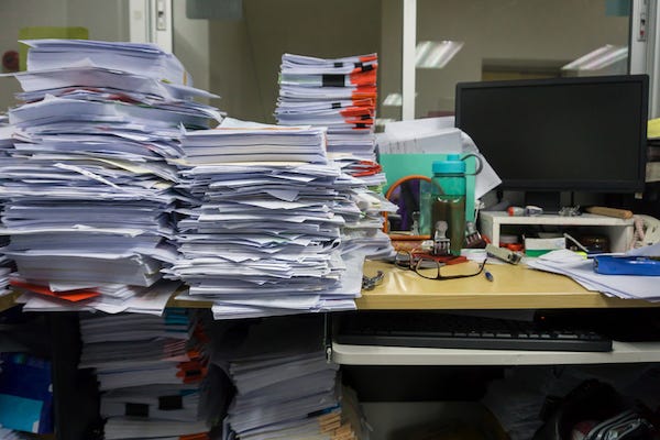 Messy desk in an office with stacks of paper