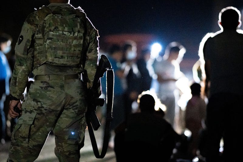 A member of the National Guard stand watch while immigrants wait to be processed after crossing the Rio Grande into the U.S. on June 16, 2021 in Roma, Texas.