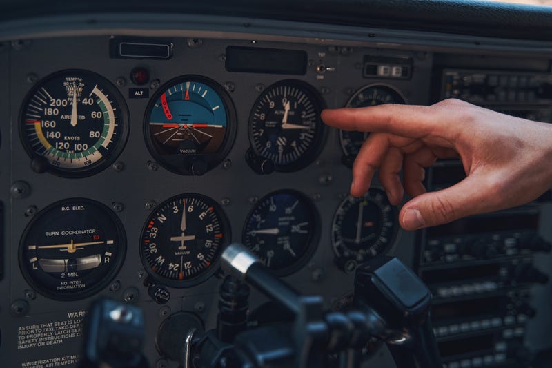 Close up of young man pilot pointing finger at flight displays in cockpit of airplane