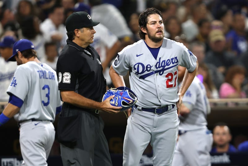 Homeplate umpire James Hoye #92 checks the glove of Trevor Bauer #27 of the Los Angeles Dodgers during the fourth inning of a game against the Los Angeles Dodgers at PETCO Park on June 23, 2021 in San Diego, California. 