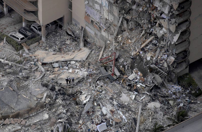 Search and rescue personnel with a K9 unit work in the rubble of a 12-story residential tower that partially collapsed on June 24, 2021 in Surfside, Florida.