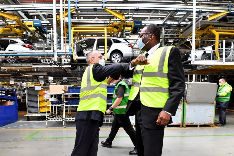 Two men in yellow vests bumping elbows in car plant