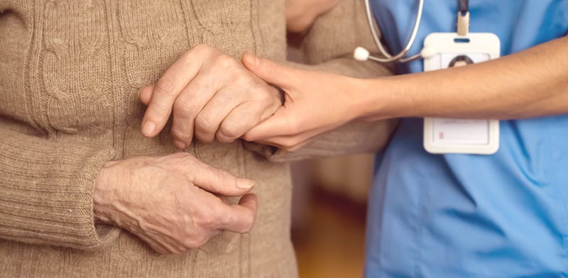 FILE: Young woman holds elderly patient's hands.